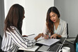 © saltdium - Photo of a young business owner signing contract at the working desk surrounded by a computer laptop and office equipment.