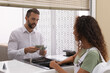 © New Africa - African American woman receiving money at cash department window in bank. Currency exchange