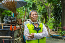 Portrait Happy Old Asian Man Street Cleaner Standing Next To An Old Gabage Cart Before Going To Work With Nature Background.
