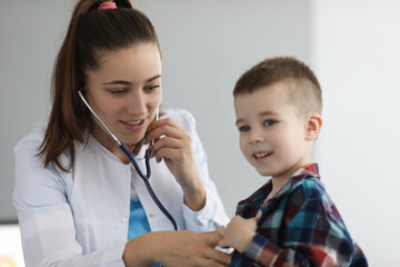 Wall Mural - Doctor pediatrician listening to heart with stethoscope to little boy in clinic