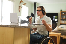 Caucasian Disabled Man Recording Podcast Using Microphone Sitting On A Wheelchair At Home