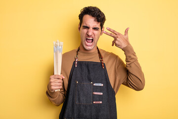 Wall Mural - young handsome man looking unhappy and stressed, suicide gesture making gun sign. artist concept