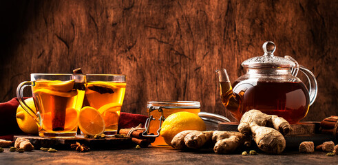 Canvas Print - Hot black winter tea with ginger, honey, lemon and spice. Immune booster drink in glass cup on rustic wooden table background, copy space