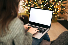 Woman Work On Laptop Computer With Blank Display Screen With Mockup Copy Space. Home Interior Decorated For Christmas Celebration With Christmas Tree And Garland Lights.