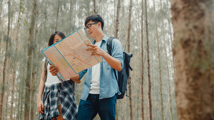 Asian hiker couple trekking in forest. Young happy backpack male and female walking enjoy her journey, travel nature and adventure trip, climb mountain lot of tree in fall holidays vacation concept.