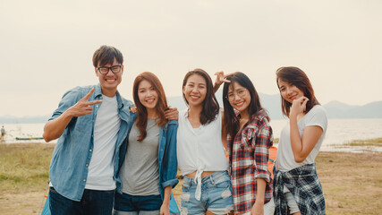 Group of Asia best friends teenagers take picture with automatic camera enjoy happy moments together beside camp and tents in national park. On the background beautiful nature, mountains and lake.