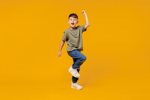 Full Body Little Small Fun Happy Boy 6-7 Years Old Wearing Green T-shirt Do Winner Gesture Clench Fist Isolated On Plain Yellow Background Studio Portrait. Mother's Day Love Family Lifestyle Concept.