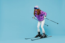 Full Body Skier Smiling Happy Fun Cool Woman 20s Wearing Warm Purple Padded Windbreaker Jacket Ski Goggles Mask Spend Extreme Weekend In Mountains Look Camera Isolated On Plain Blue Background Studio