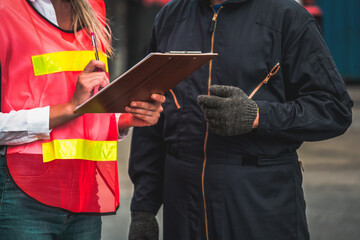 Industrial worker works with co-worker at overseas shipping container yard . Logistics supply chain management and international goods export concept .