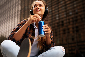 Wall Mural - Fashion woman with skateboard. Urban brunette woman listening the music.