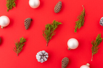 Wall Mural - New Year and Christmas background. Minimalism. On a red background, small coniferous branches, cones, balls. New Year, Christmas, winter holidays, congratulations, invitation, interior decor.