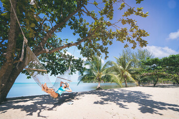 Wall Mural - Vacation concept. Enjoying the summer. Young pretty woman in hat and sunglasses laying in hammock on the beach.