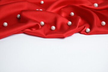 Texture of delicate red silk with pearls on white background