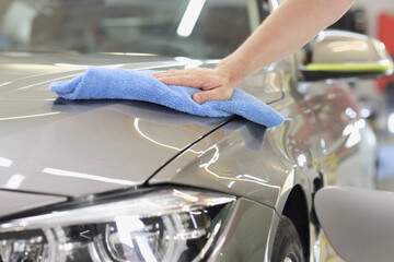 Wall Mural - Male hand wiping hood of car with microfiber cloth closeup