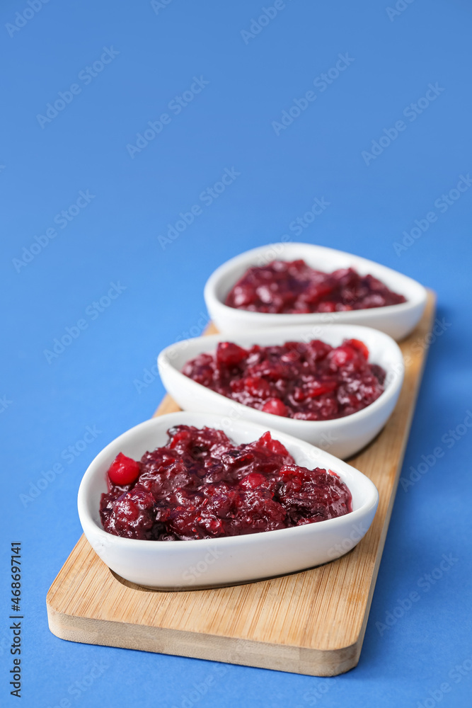 Bowls of tasty cranberry jam on blue background