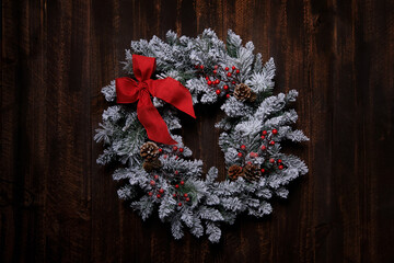 Wall Mural - Snowy Christmas Wreath on a Wooden Background With Red Bow