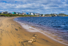 Sandy Beach Of Aguanish On A Summer Day, With The Small Fishing Town Of Aguanish In The Beackground, Located In Cote Nord Region Of Quebec, Canada