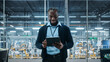 © Gorodenkoff - Car Factory Office: Portrait of Successful Black Male Chief Engineer Using Tablet Computer in Automated Robot Arm Assembly Line Manufacturing High-Tech Electric Vehicles. Medium Shot