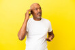 © luismolinero - Cuban Senior isolated on yellow background keeping a conversation with the mobile phone with someone
