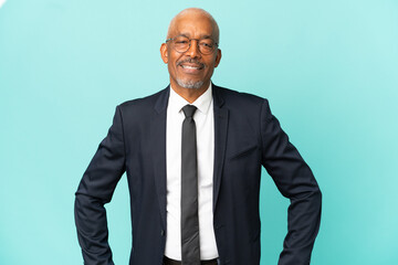 Wall Mural - Business senior man isolated on blue background posing with arms at hip and smiling