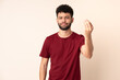 © luismolinero - Young Moroccan man isolated on beige background making Italian gesture