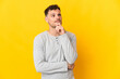 © luismolinero - Young caucasian handsome man isolated on yellow background and looking up