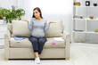 © Andrii - Photo of pregnant woman sitting on the sofa with child clothes.