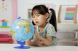 © M-image - young girl learning world globe at home