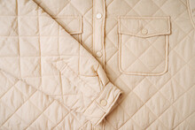 Quilted Material, Square Quilted Jacket With Pocket. Beige  Background Texture. Close-up