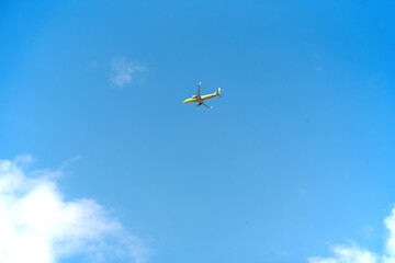 yellow passenger plane under clouds in a blue sky - Travel by air