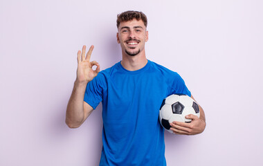 young handsome man feeling happy, showing approval with okay gesture. soccer concept