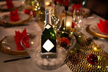 Wall Mural - champagne bottle on a christmas holiday festive party table with wine glass on a red and gold shiny decoration