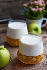 Sticker - Panna cotta with apple layer. Side view, wooden background.