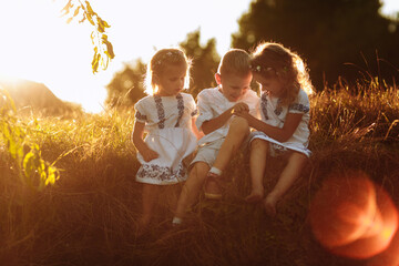 Kids, boy and girls are playing, joking, having fun at sunset in the park on the green grass. Children's games, leisure. happy childhood