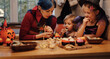 © YURII Seleznov - Mother and her daughters having fun at home. Happy Family preparing for Halloween. Mum and kids taste, decorated festive fare at kitchen.