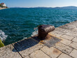 Giant iron boat tie-up on dock in Zadar, Croatia with Adriatic Sea in the background.
