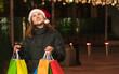 © Наталья Жукова - girl in a red santa claus hat with gifts in hands on the street of the city. Christmas mood