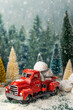 Christmas scene with cookies in a red truck between evergreen trees in snow