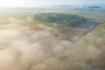 Aerial view of foggy autumn field and forest landscape. View of a small village in the morning, drone