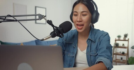 Wall Mural - Happy asia girl record a podcast on laptop computer with headphones and microphone talk with audience at living room. Female podcaster make audio podcast from her home studio. Stay at house concept.