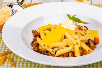 Wall Mural - Penne pasta with pumpkin, tofu and mushrooms on white plate. Close up