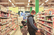 © Татьяна - Man in protective medical mask buying food at grocery store or supermarket during quarantine, lockdown, coronavirus pandemic.