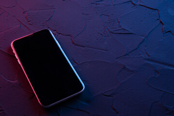Mobile smartphone on dark red blue neon colors. Mock up.Perspective view. The layout of the device. Presentation of the interface design.