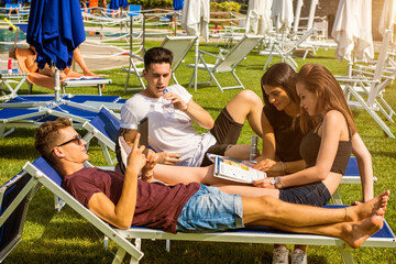 Friends relaxing on sun loungers in beautiful sunny day.