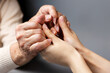 © _KUBE_ - Mother and daughter holding hands. Close-up. Gray background. The concept of caring for the elderly people