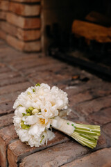 Canvas Print - Vertical shot of a beautiful, white  brides flower bouquet on the wall with bricks