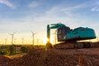 Backhoe and wind turbines that are generating electricity in the background, the concept of sustainable resources, Beautiful sky with wind generators turbines, Renewable energy