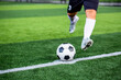 Selective focus to soccer ball with blurry soccer player run to shoot it.