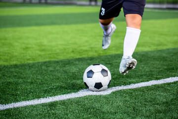 Wall Mural - Selective focus to soccer ball with blurry soccer player run to shoot it.