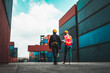 © InfiniteFlow - Industrial worker works with co-worker at overseas shipping container yard . Logistics supply chain management and international goods export concept .
